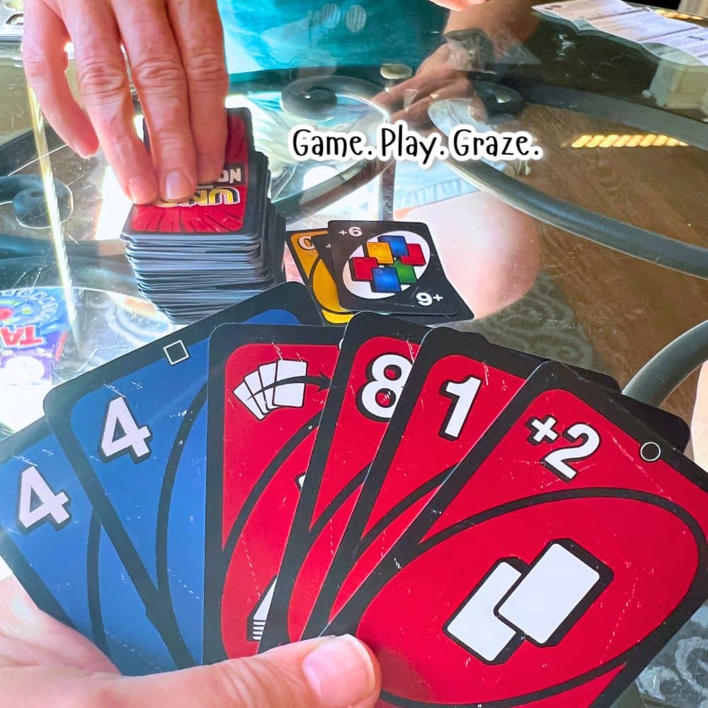 Uno Show Em No Mercy Card Game Review For Game Night playing cards on a game table for the UNO SHOW EM NO MERCY card game for family game night or game party games